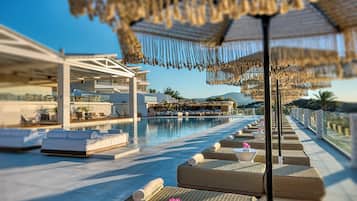 A luxurious poolside area with sun loungers, a pool, and a view of the mountains.