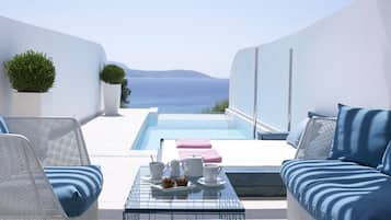 Ein moderner Außenbereich mit Pool, weißen Wänden und Meerblick.