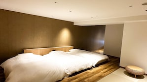 Un dormitorio moderno con suelo de madera, una cama grande y una pequeña mesa redonda.