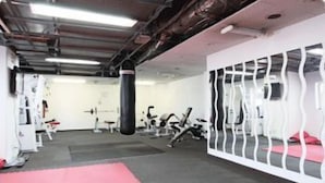 Un gimnasio con equipo de ejercicio, un saco de boxeo y una pared blanca con un diseño decorativo.