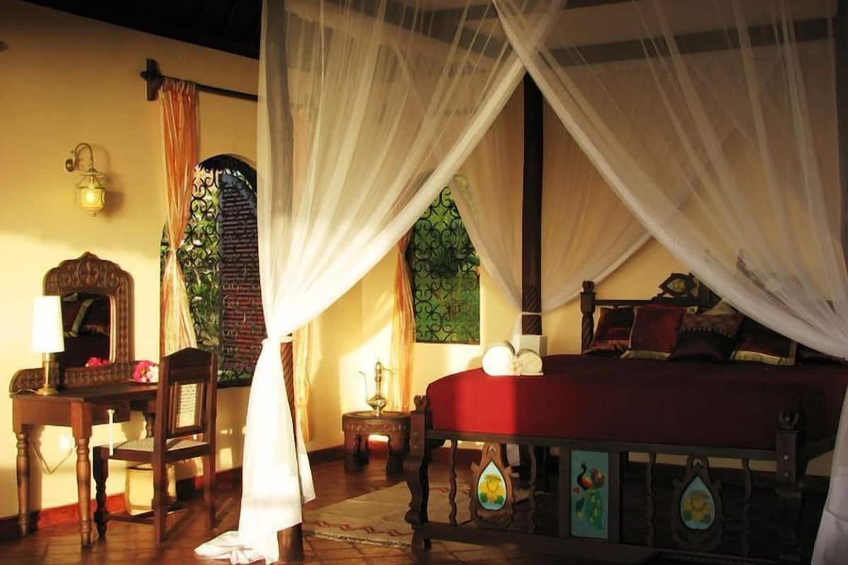 A room with a bed, a chair, a table, and a lamp.