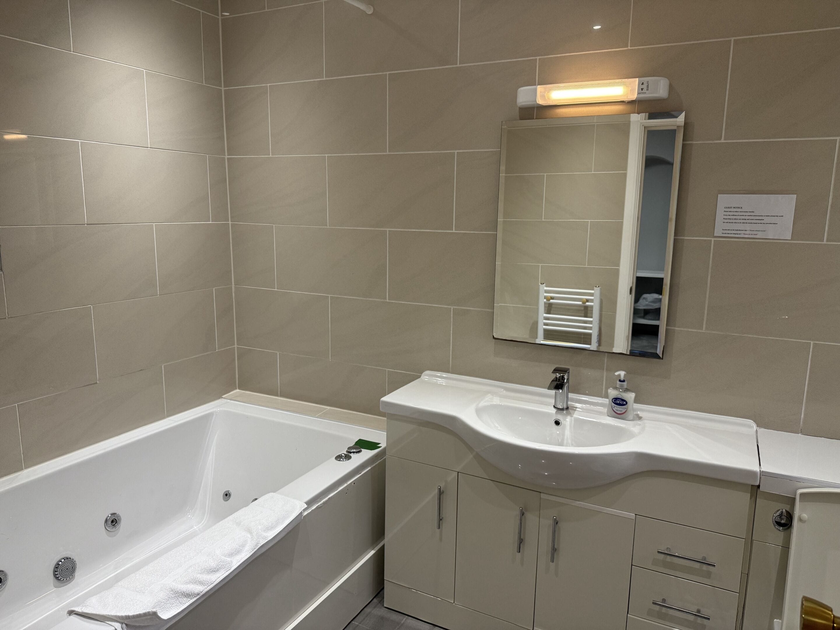 Un bagno con una vasca, un lavandino e uno specchio.