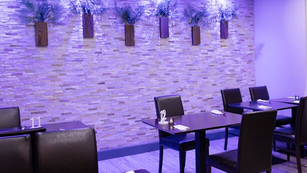 A restaurant with a brick wall, wooden tables, and chairs. - The County Hotel (Helensburgh)