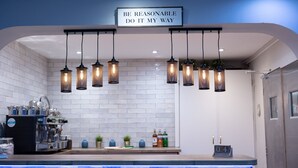 A modern kitchen with a stone countertop, hanging pendant lights, and a sign above stating "BE REASONABLE DO IT MY WAY". - The County Hotel (Helensburgh)