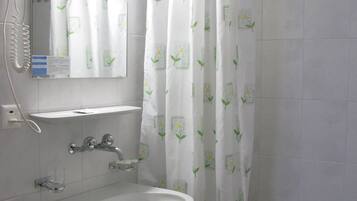 Un baño con lavamanos blanco, un espejo, un secador de pelo y una cortina de ducha con estampado floral.