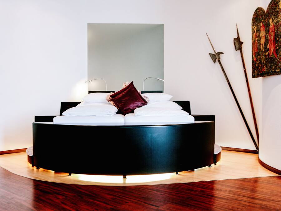 A modern bedroom with a round bed, a large mirror, and a painting on the wall.