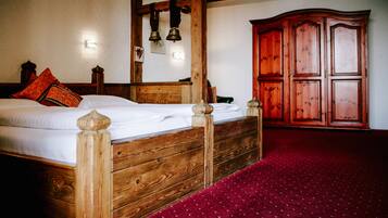 A wooden bed with a headboard, a red carpet, and a wooden wardrobe in a room.