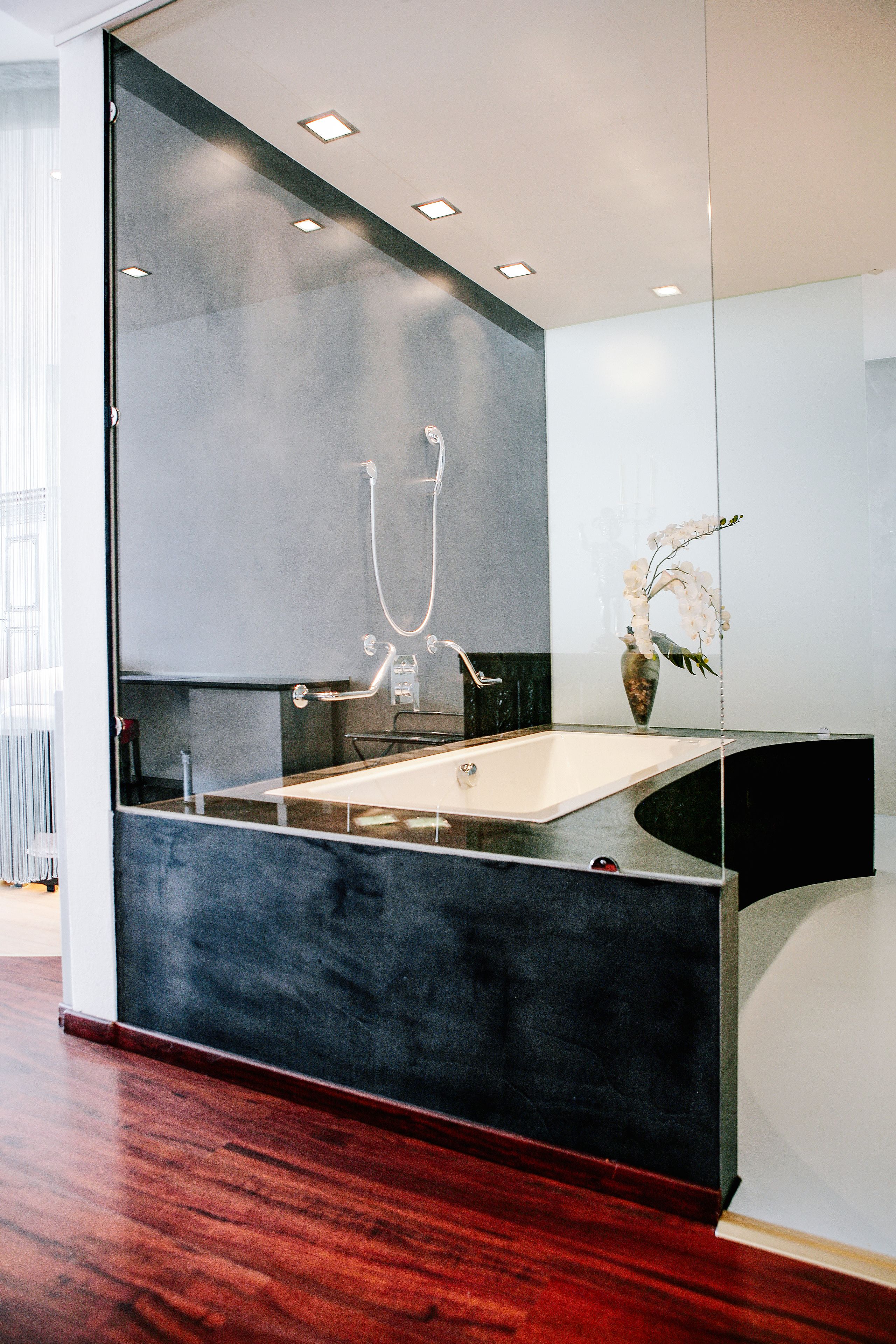 A modern bathroom with a glass-enclosed shower, a white sink, and a vase with flowers.