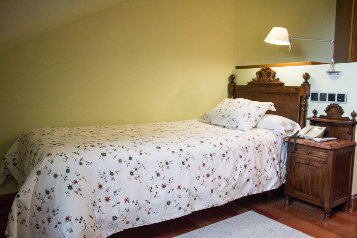 Un dormitorio con cama, mesita de noche, lámpara y cabecero de madera.