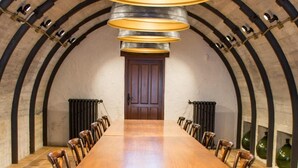 A long wooden table with chairs, a large hanging light fixture, and a door in a vaulted room with tiled flooring. - Mirador de Moriyón (Villaviciosa)