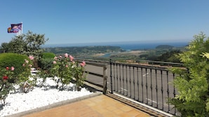 A balcony with a view of a coastal landscape, a flag, and a garden with pink flowers. - Mirador de Moriyón (Villaviciosa)