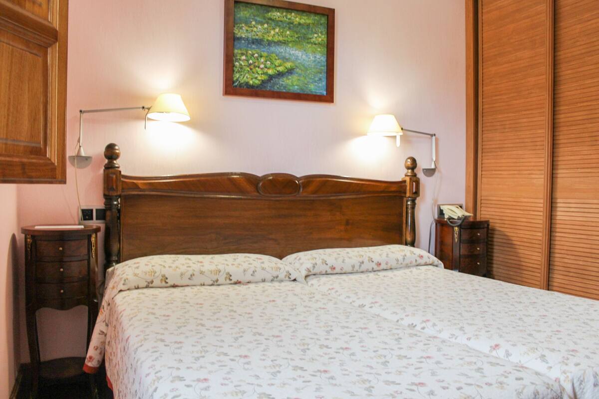 Un dormitorio con cabecera de madera, dos mesitas de noche y un cuadro en la pared.