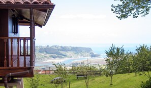 A wooden cabin with a balcony overlooking a coastal landscape.