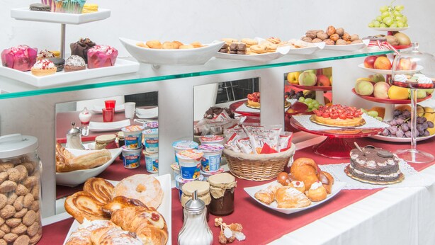 Een buffet met diverse gerechten, waaronder gebak, fruit en desserts.
