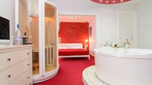 Een moderne badkamer met een groot wit bad, een rood vloerkleed en een houten wastafelmeubel met lades.