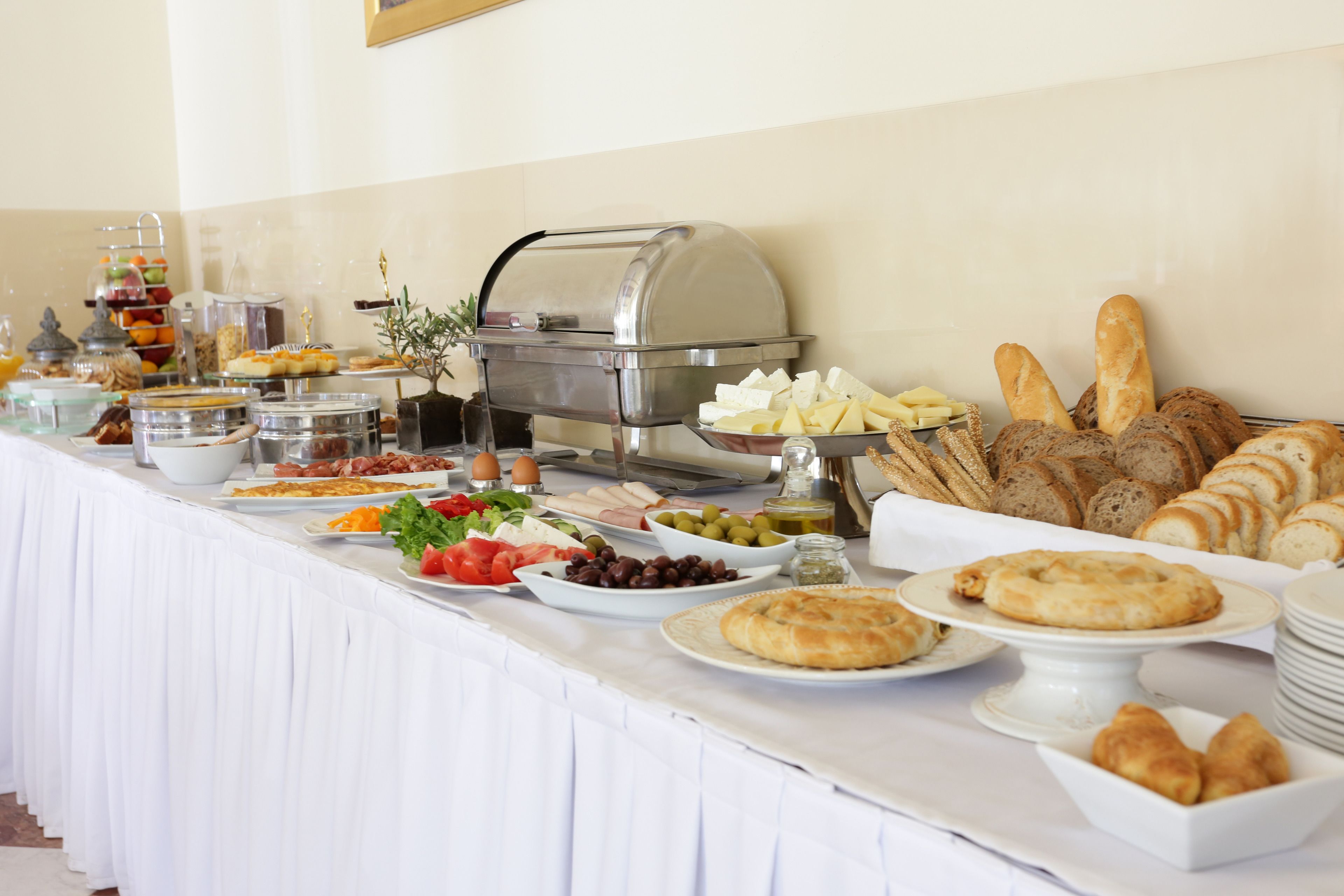 Una mesa de buffet con diversos alimentos, como pan, queso, aceitunas y ensaladas.