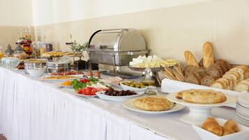 Una mesa de buffet con diversos alimentos, como pan, queso, aceitunas y ensaladas.