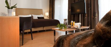 Una habitación de hotel con una cama, un escritorio, una silla, un televisor y una planta.