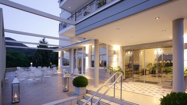 Fachada moderna de un hotel con asientos al aire libre, una escalera y entrada de vidrio.