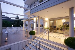 A modern hotel exterior with outdoor seating, a staircase, and a glass entrance. - Chloe Hotel (Kastoria)
