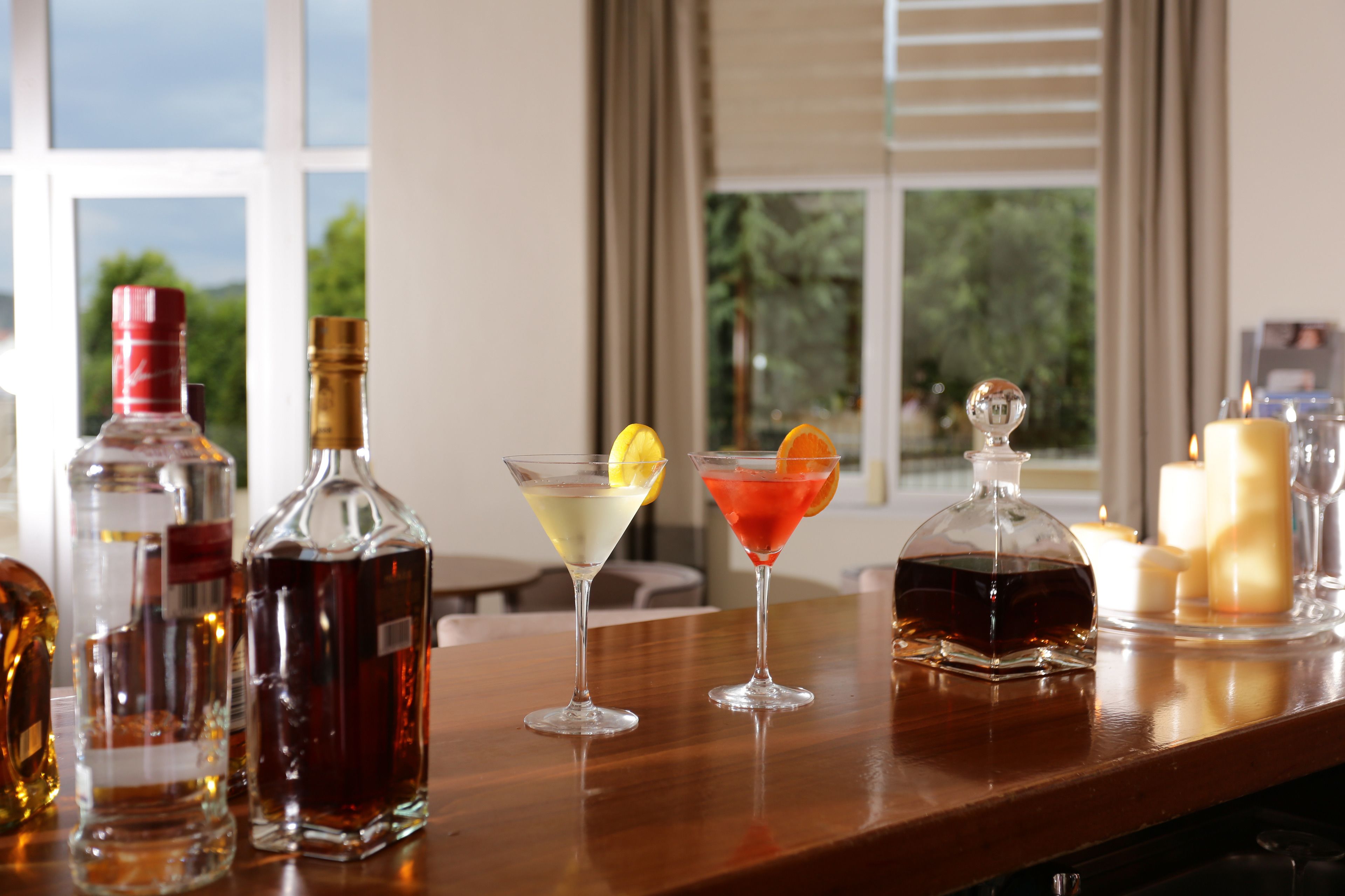 A bar area with various bottles and glasses, including a decanter and a bottle with a red cap.