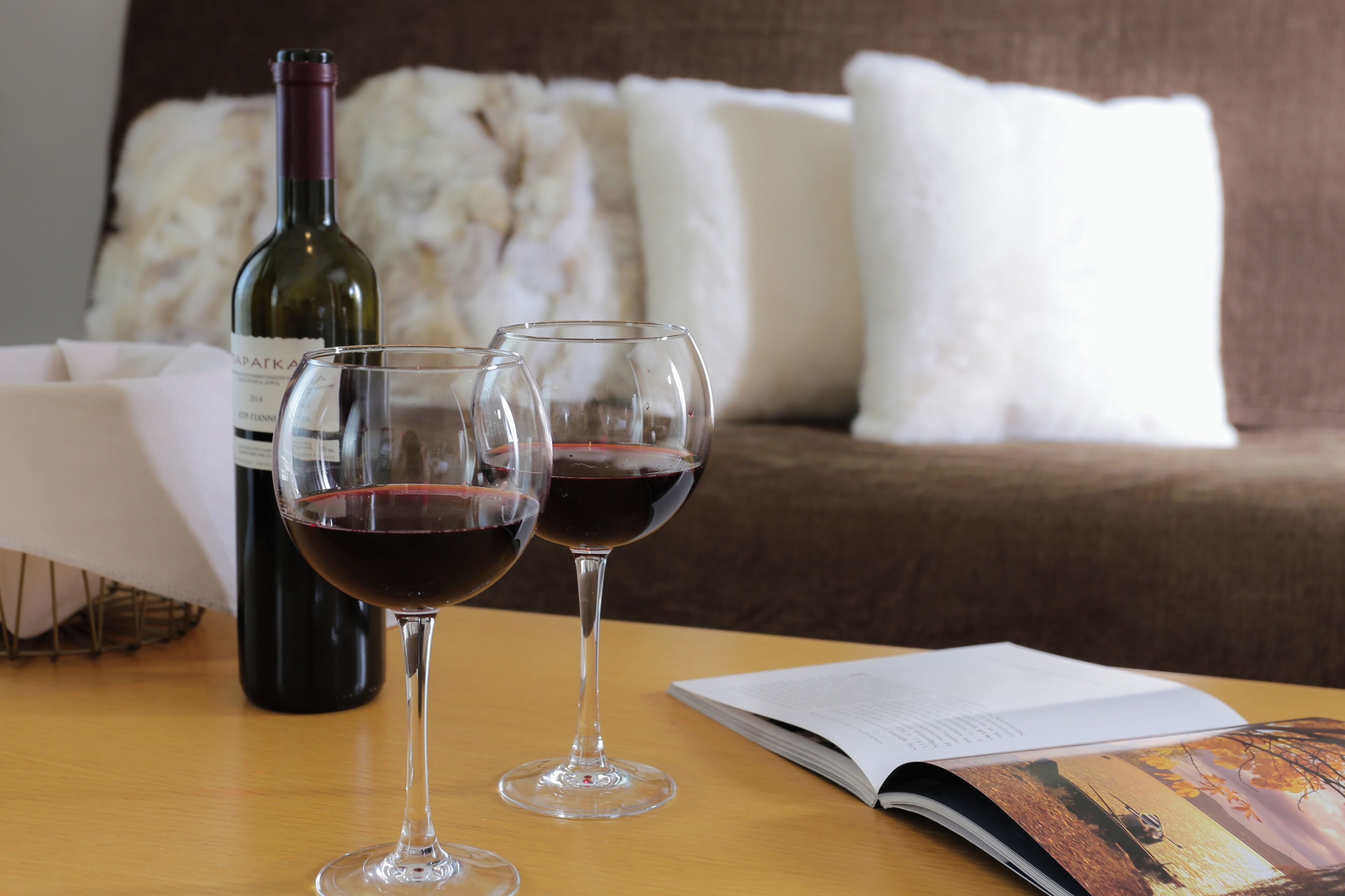 Une bouteille de vin et deux verres sur une table, à côté d’un livre ouvert.