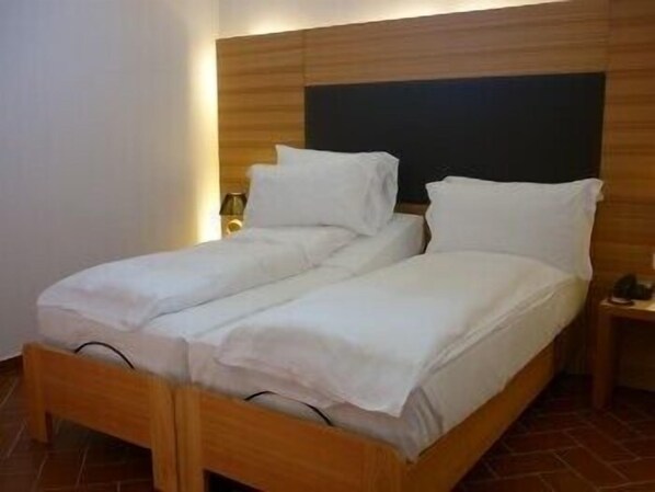 A double bed with white linens in a room with wooden headboard and nightstands.