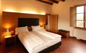 A double bed with a wooden headboard, two bedside tables with lamps, a bench, and a window with a view. - Relais Palazzo Lodron - Guest House (Nogaredo)