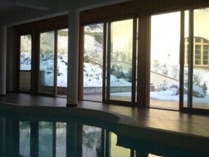 A swimming pool with large glass doors leading to a snowy outdoor area. - Relais Palazzo Lodron - Guest House (Nogaredo)