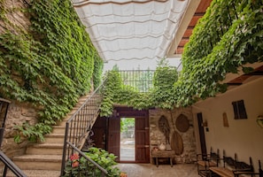 Una escalera de piedra con una puerta de madera en la parte superior, rodeada de abundante hiedra verde.