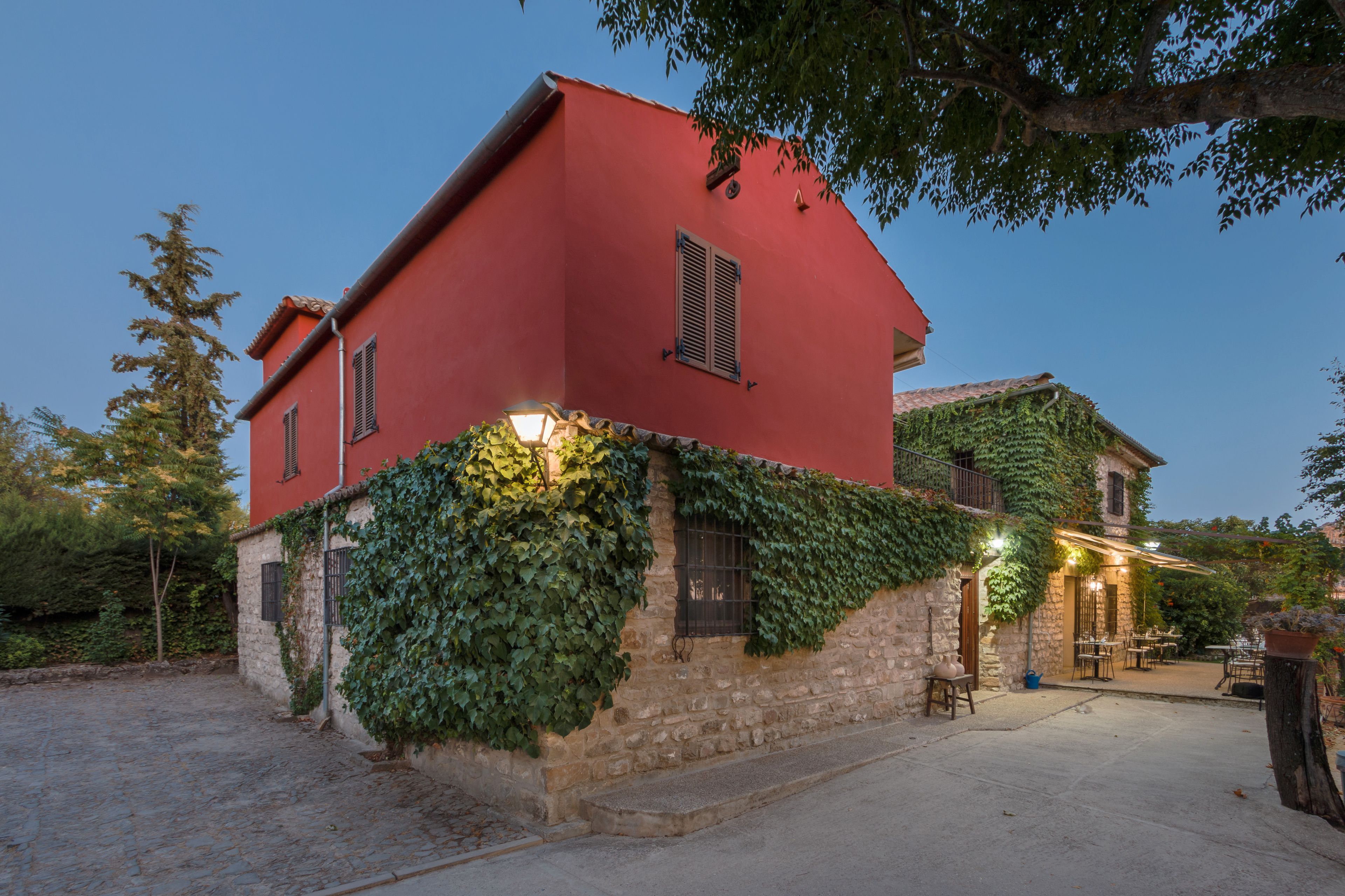 A red building with stone walls and ivy.