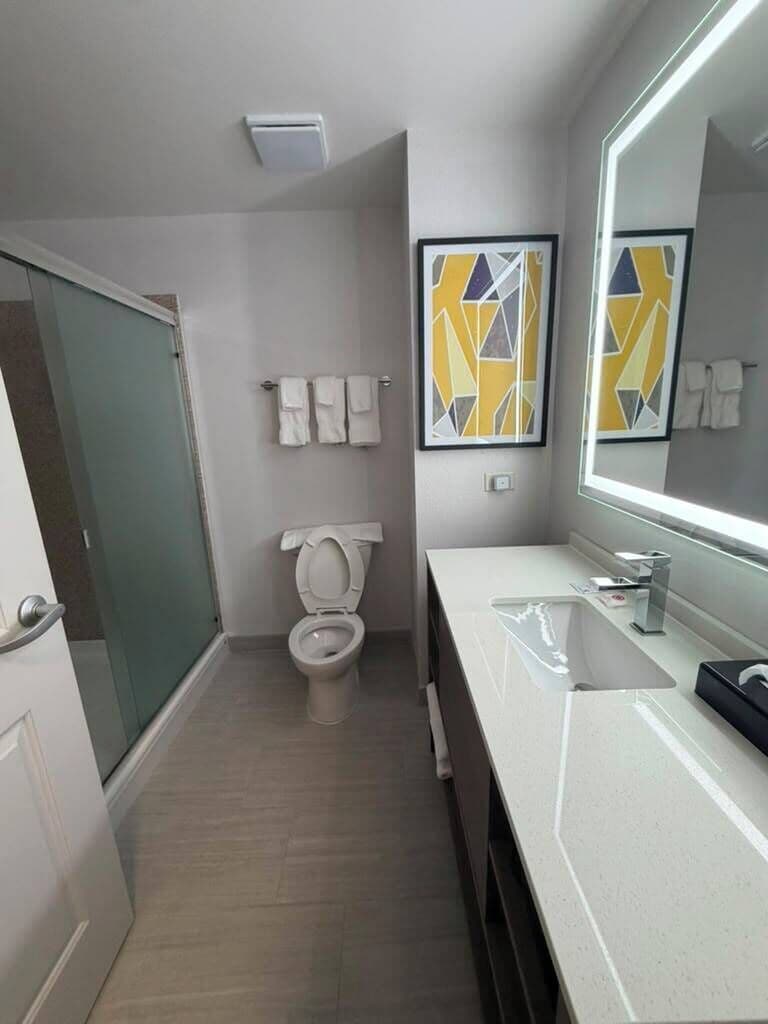 A modern bathroom with a toilet, sink, and mirror.