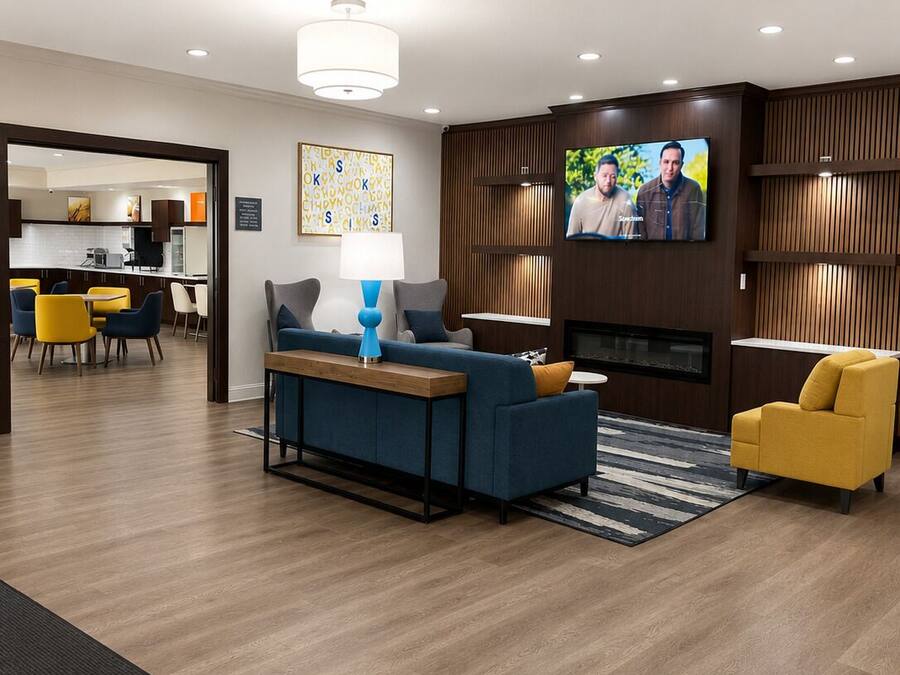 Una sala moderna con sofá, una mesa de centro, televisor y una cocina visible a través de una puerta abierta.