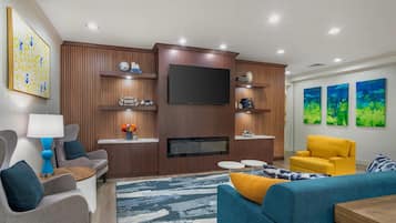 A modern living room with a flat-screen TV, wooden paneling, a sofa, a coffee table, and a yellow armchair.