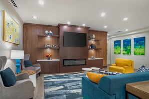 A modern living room with a flat-screen TV, wooden paneling, a sofa, a coffee table, and a yellow armchair.