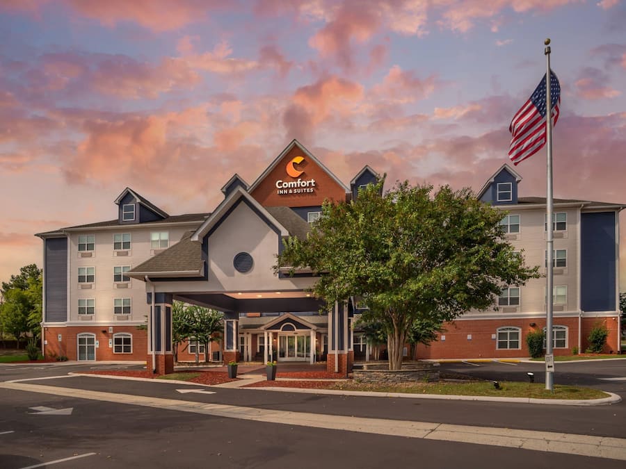 Et Comfort Inn & Suites hotel med murstensfacade, en overdækket indgang og et amerikansk flag.