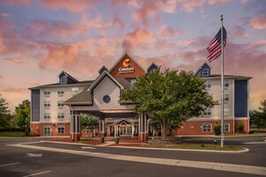 Un hotel Comfort Inn & Suites con fachada de ladrillo, un acceso cubierto y una bandera estadounidense.