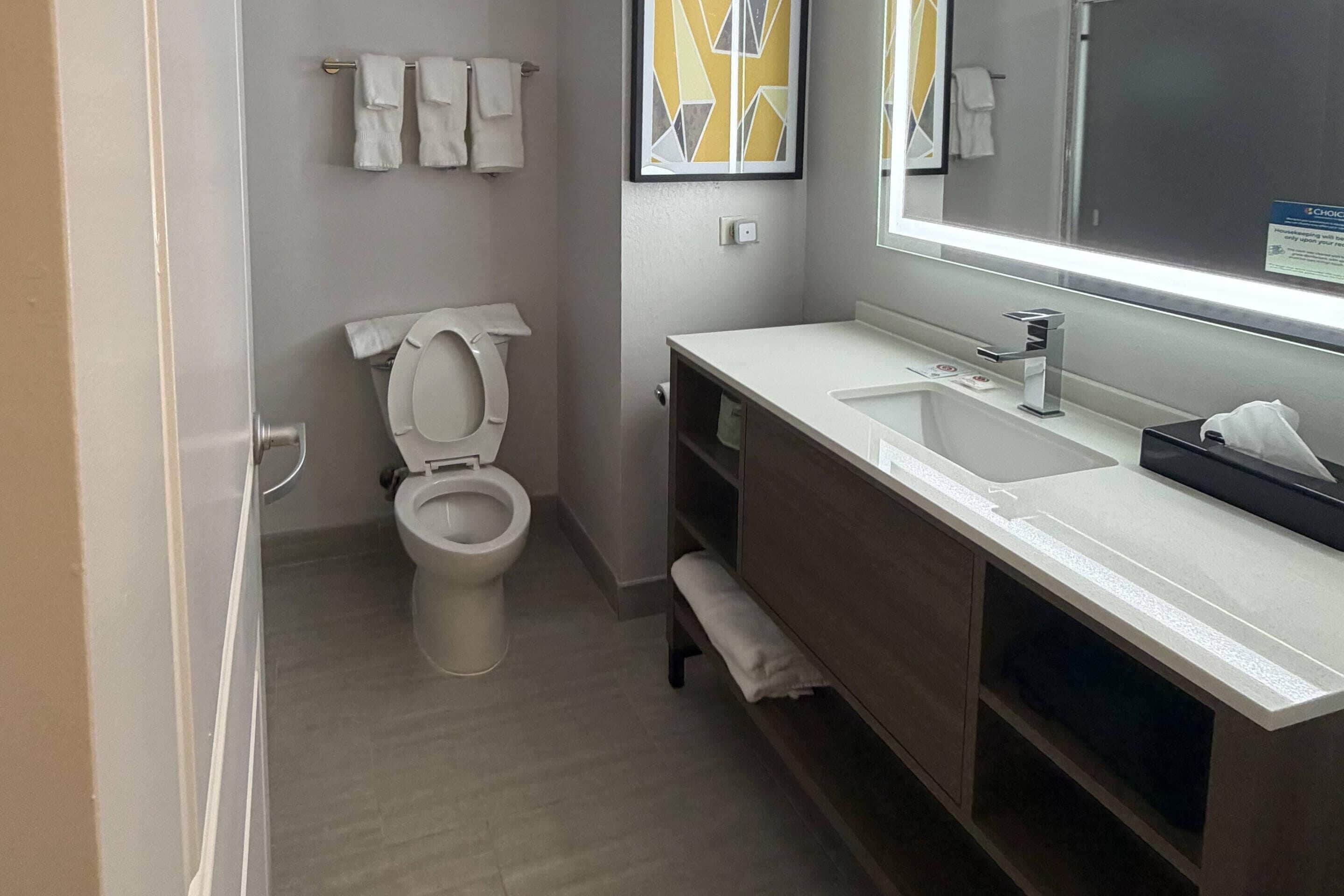 Un baño moderno con inodoro, lavamanos y espejo.