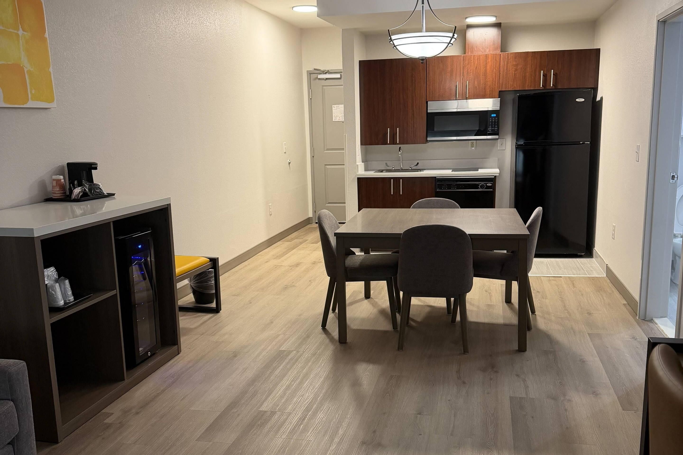 A compact kitchen with a dining table, chairs, a microwave, and a refrigerator.