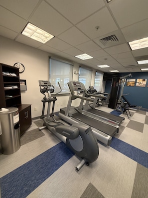 A gym with treadmills, elliptical machines, and a mirrored wall.