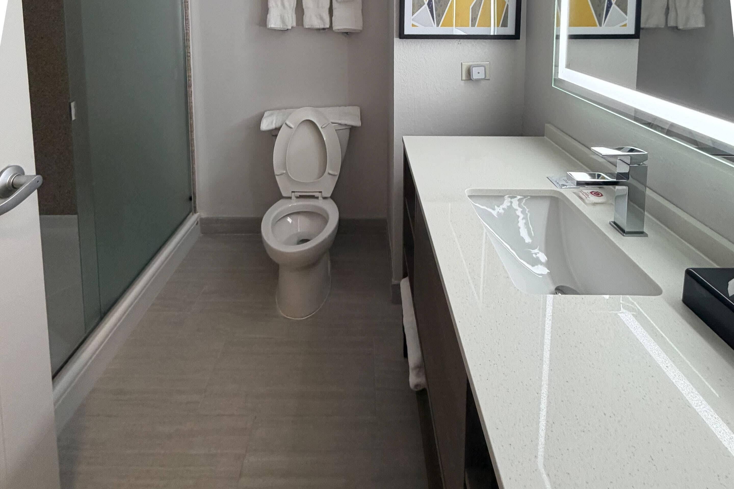 A modern bathroom with a toilet, sink, and mirror.