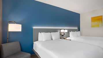 A hotel room with a large bed, a bedside table with a lamp, a chair, and a painting on the wall.