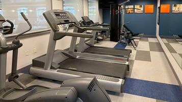 A gym with treadmills, a weight machine, and a mirrored wall.