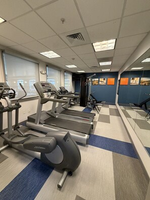 Ett gym med löpband, crosstrainers och en vägg med speglar.