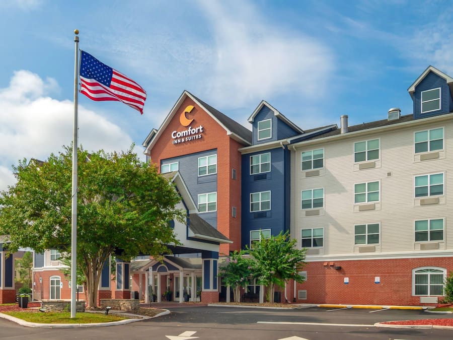 A Comfort Inn & Suites hotel with a brick facade, multiple windows, and a flagpole with an American flag.