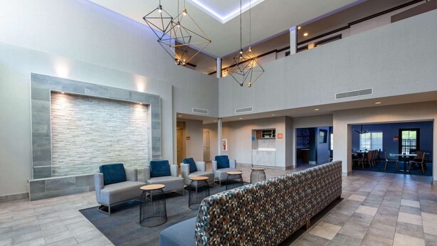 A spacious lobby with a long bench, seating area, and a reception desk. - La Quinta Inn & Suites by Wyndham Las Vegas Airport South (Las Vegas)