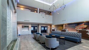 A spacious lobby with a high ceiling, a reception desk, a seating area with sofas and chairs, and a prominent 'Welcome to Las Vegas' sign. - La Quinta Inn & Suites by Wyndham Las Vegas Airport South (Las Vegas)
