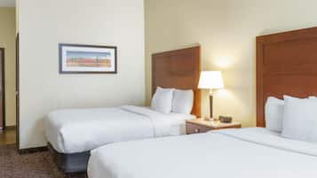 Een hotelkamer met twee bedden, een televisie, een lamp, een schilderij en een deur.