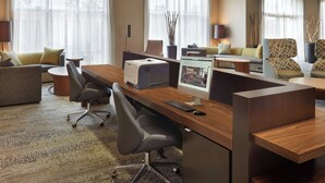 Una habitación de hotel moderna con un escritorio de madera, computadora y zona de estar cómoda.