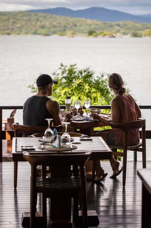 A couple dining at a wooden table with a view of a lake and mountains. - Jicaro Island Lodge Member of the Cayuga Collection (Granada)